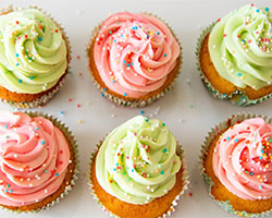 Six cupcakes with pink and green icing and rainbow sprinkles