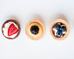 Three Small Party Cakes, each have a different berry on top, strawberry, blackberry, blueberry